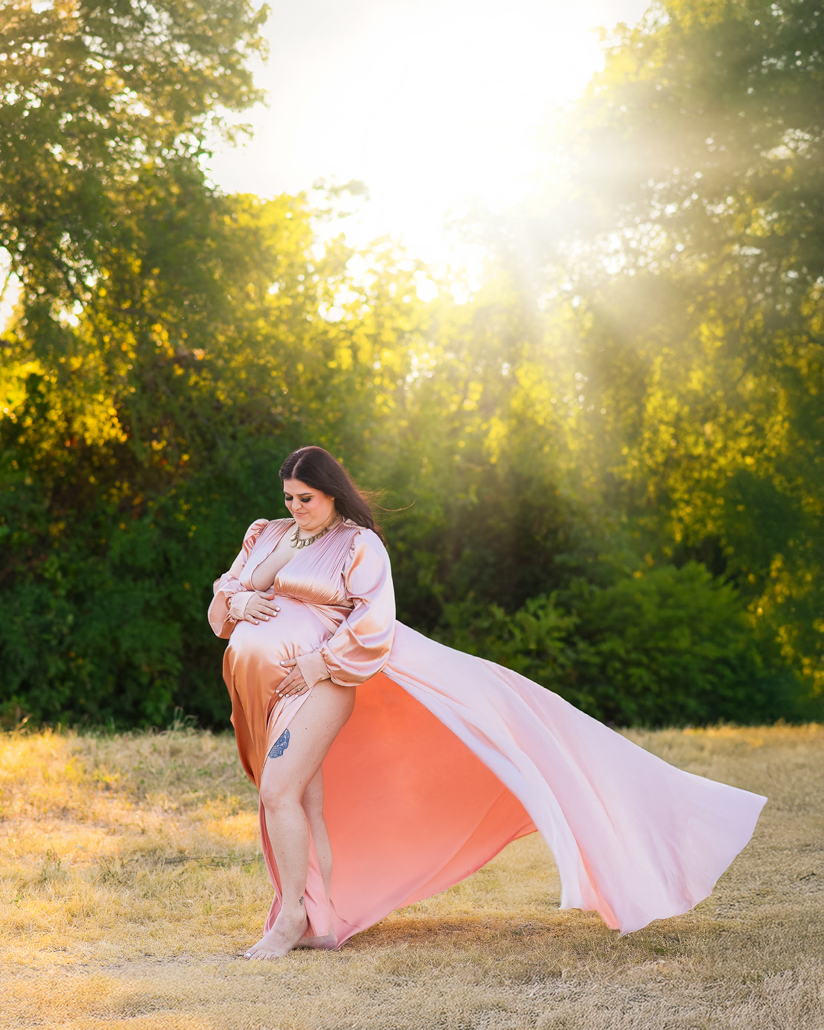 Dreamy outdoor maternity portrait of a mother in a flowing pink gown during golden hour in Benbrook, Texas